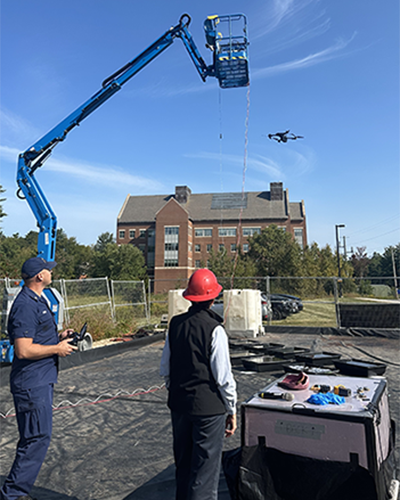 Drone pilot flies drone pilot demonstrates flying drone over oil in plastic tubs to detect oil pollution.