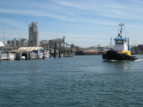 A boat navigates the Lower Duwamish River with industrial development on both sides of the river's banks.