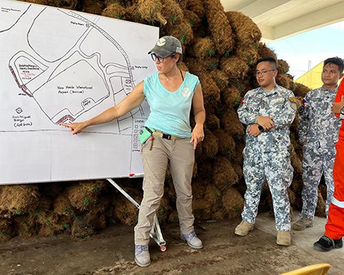 Individual points to visual diagram of shoreline oil conditions with members of Philippines Coast Guard.