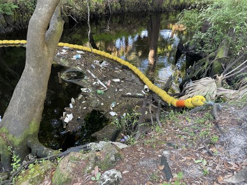 Litter captured in a river by an installed boom-style interception device.