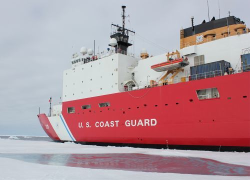 Red and white ship on ocean with ice.