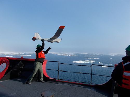 Man on ship holding mini plane.