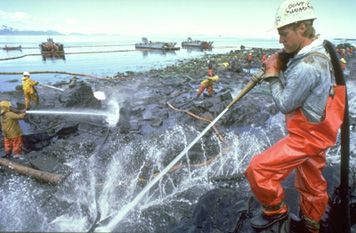 Photo: Cleanup workers spray oil-covered rocks with high-pressure hoses.