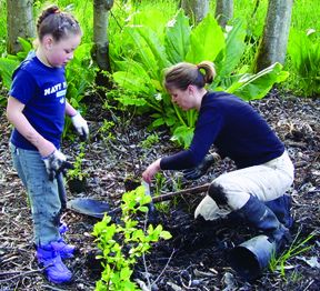 Photo: A woman and child work to plant vegatation 