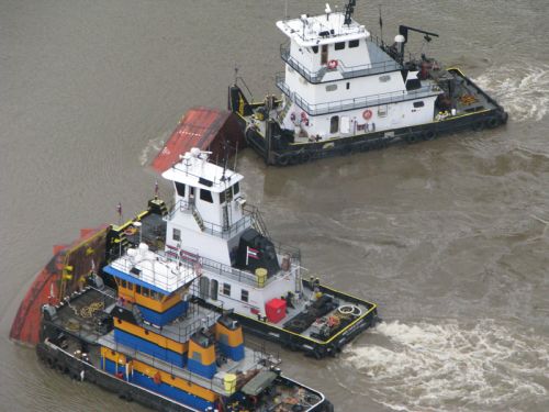 Tugs respond to the submerged Barge DM932.