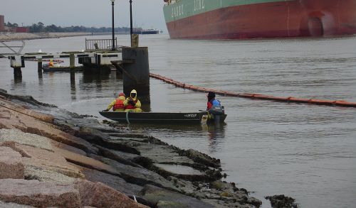 Workers clean oil from rocks following spill.