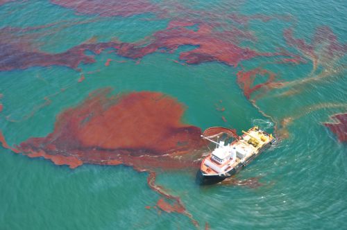 Ship using a skimmer to collect spilled oil.