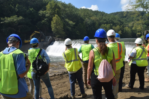 People in hard hats and vests near a body of water.