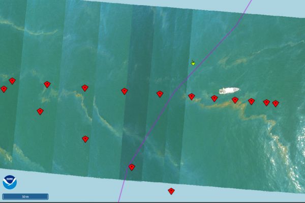 Nadir images, &quot;tagged&quot; with red kite icons, are stitched together into a mosaic image map. The nadir images capture a top-down view of a vessel on open water next to observed oil sheen.