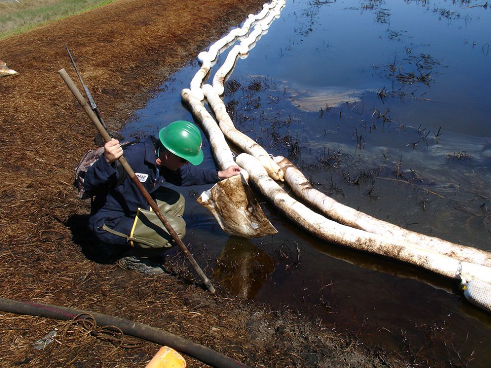 Man examining oil in a pond.