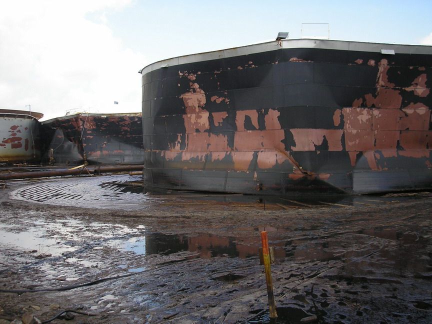 Large oil tank with oil pooled around it.