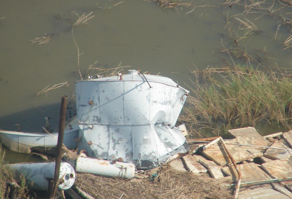Damaged tank partially on a dock, partially in water.