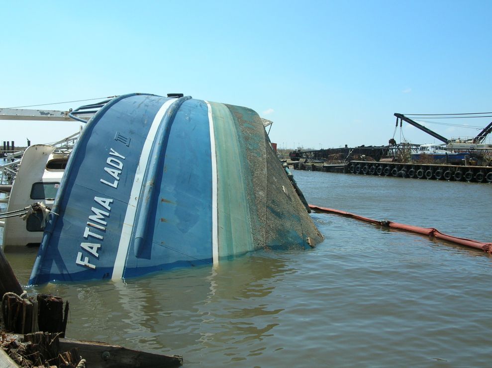 Overturned fishing vessel in water.
