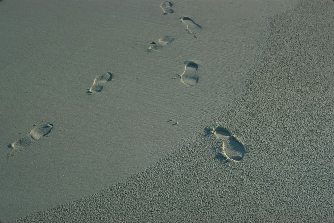 Photo of footprints on sand.