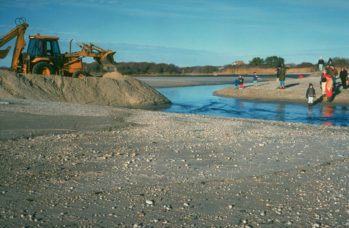 Photo of excavator and people on shore.