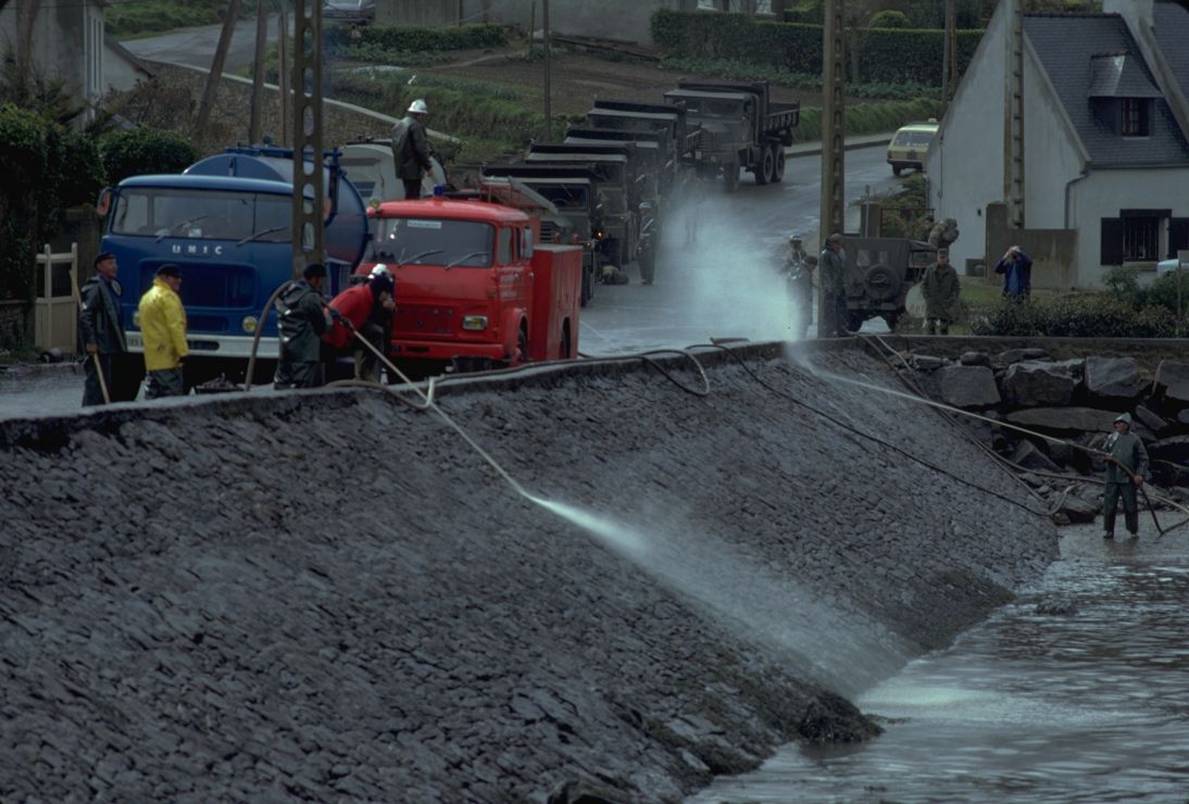Photo of workers power-spraying water on riprap.