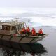 People on the Arctic Survey Boat amid icy waters.