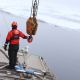 U.S. Coast Guard member prepares a crane to launch small survey boat.