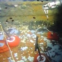 An underwater image of the hull of a vessel with equipment on it. 