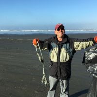 Man holding up a piece of debris on a beach.