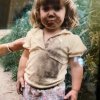 A child with mud on her face and clothes. 