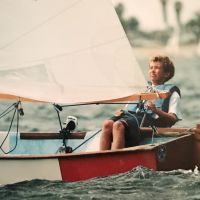 A young boy on a small sailboat. 