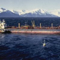 A vessel in water with snowy mountains in the background.