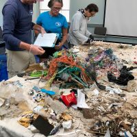 People standing by a table full of marine debris samples.