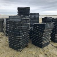Plastic, large plastic bins stacked on a beach.