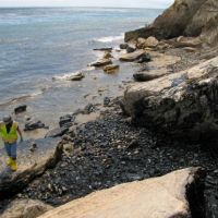 Cleanup worker and oiled boulders on Refugio State Beach where the oil from the pipeline entered the beach. Image: NOAA.