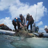 Image of scientists pulling discarded nets onto their boat.