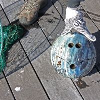 A cracked bowling ball with a net used to scoop it out of a river.