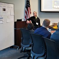 An instructor presenting in front of a white board going through a situation status briefing regarding the class scenario to answer "What can be done?" Photo Credit: NOAA