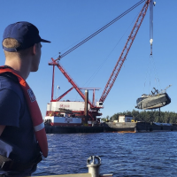 A Coast Guard member watches the F/V Aleutian Isle being lifted onto a barge off San Juan Island on Sept. 21, 2022. Image credit: U.S. Coast Guard