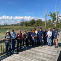 Trainee class poses together for a group photo in a marshy Great Lakes natural environment.