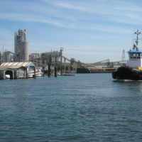 A boat navigates the Lower Duwamish River with industrial development on both sides of the river's banks.