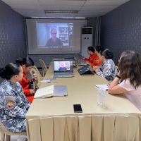 NOAA and Philippines response specialists convened around a conference table while conferencing with an individual remotely, visible on a large screen in the background.