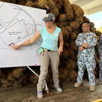 Individual points to visual diagram of shoreline oil conditions with members of Philippines Coast Guard.