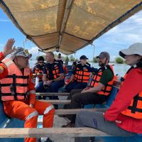 Individuals donning life jackets aboard a small vessel with a canopy.