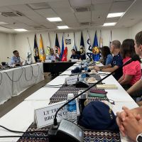 Individuals with varying affiliations convened at desks arranged in a semi-circle formation to discuss current and future oil and vessel salvage operations.