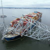 An aerial view of bridge section that lies across the bow of a large container ship after collapse. 