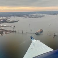March 28, 2024: View from NOAA King Air N68RF aircraft during a navigation survey following the collapse of the Francis Scott Key Bridge in Baltimore. The bridge and the MV Dali, the container ship involved in the incident, are visible. (Image credit: Lt. Eric Fritzsche/NOAA Corps).