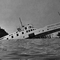 A steamship half submerged after hitting rocks.