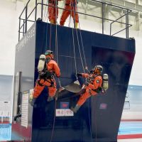 Four individuals demonstrate patching a vessel at a training facility.