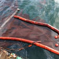 Close up of skimming device on side of a boat with oil and boom. Image Credit: U