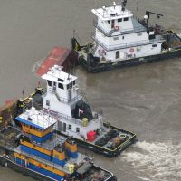 Tugs respond to the submerged Barge DM932.