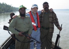 Gary Shigenaka (center) with two unidentified guards standing on a small vessel on the water.