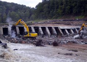 Heavy equipment being operated at the site of an old dam.