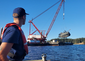 A Coast Guard member watches the F/V Aleutian Isle being lifted onto a barge off San Juan Island on Sept. 21, 2022. Image credit: U.S. Coast Guard.