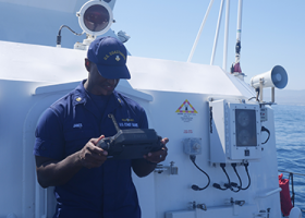 U.S. Coast Guard drone pilots operating a commercial drone controller from the Coast Guard Cutter Blackfin. 